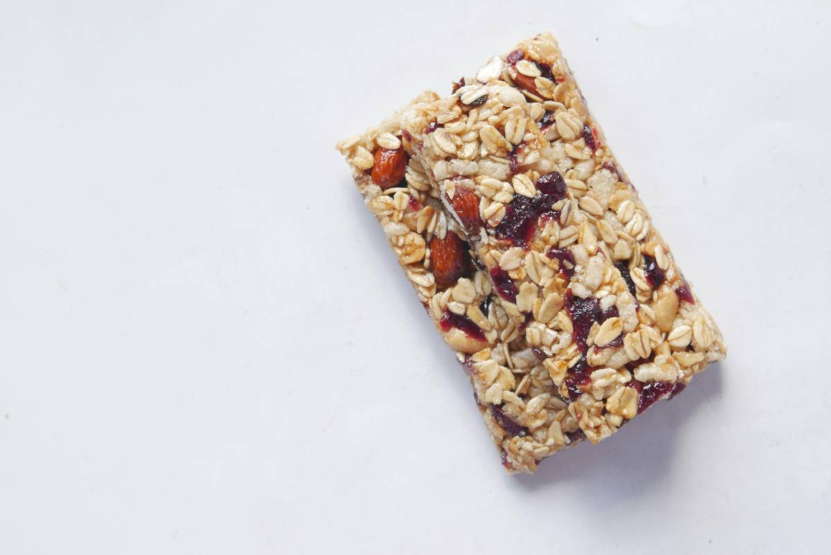 Muscle fuel snacks including protein bars, nuts, and fruit arranged on a gamer desk next to a keyboard