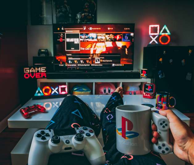 Two gamers reviewing snacks at a desk lit by RGB lights, with empty wrappers and notebooks full of ratings